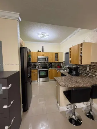 a kitchen with stainless steel appliances granite countertop a refrigerator a stove and a sink