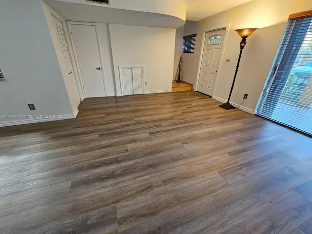 a view of a room with wooden floor and white walls