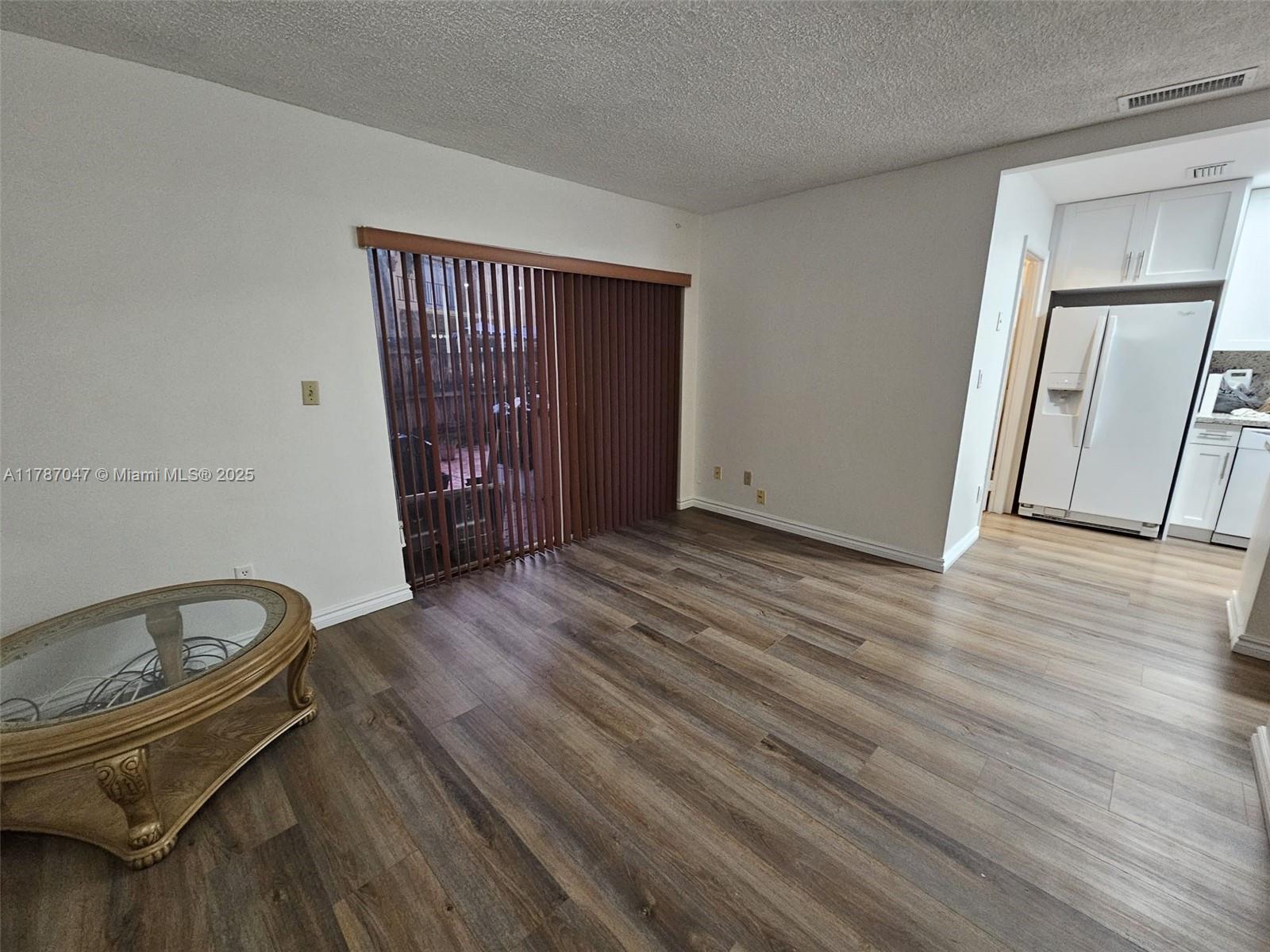 13745 Southwest 84th Street, Unit A Miami, FL 33143 - Photo 2 of 16 a view of an empty room with wooden floor and a window