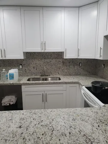 a kitchen with granite countertop a sink and cabinets