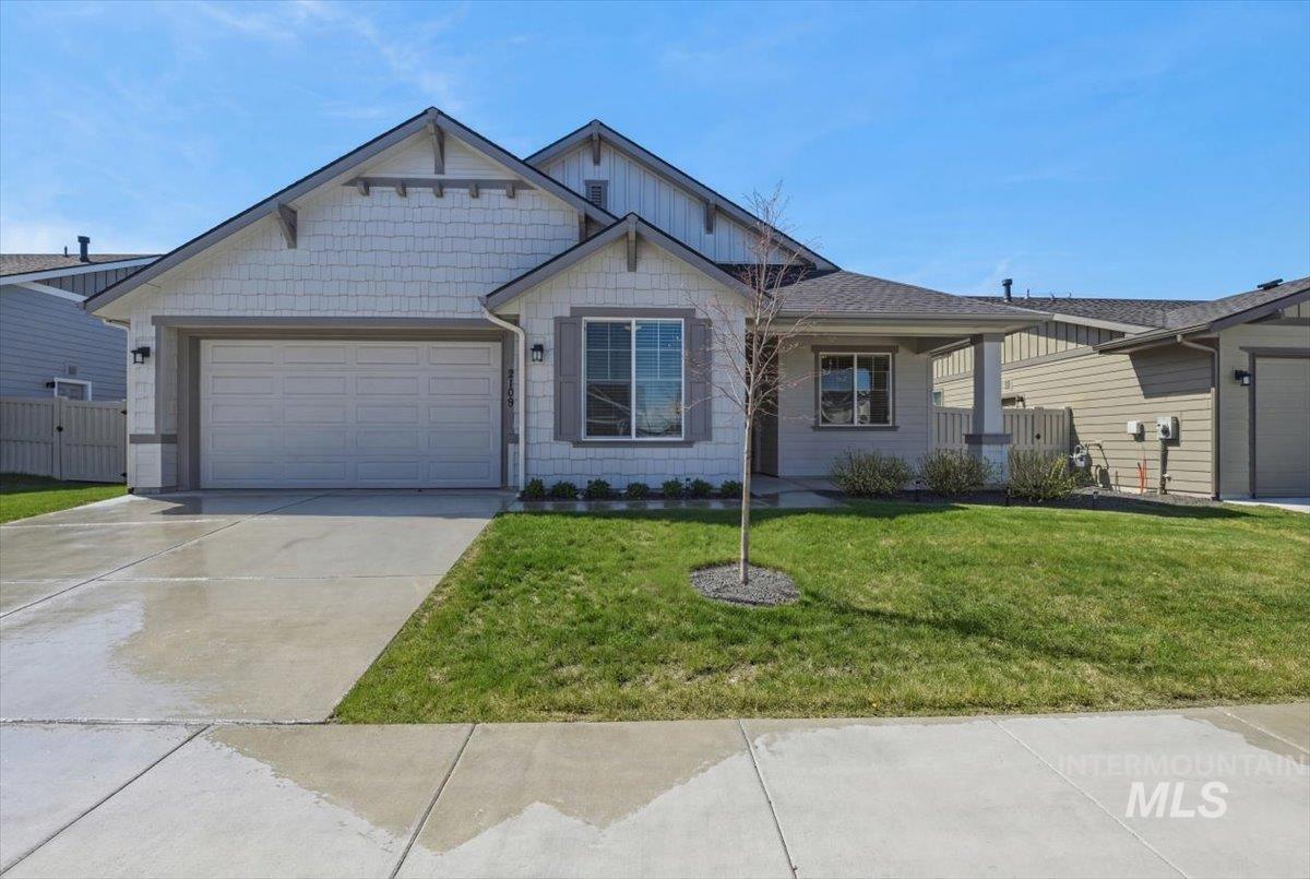 View of front of house featuring an attached garage, covered porch, a front yard, and concrete driveway