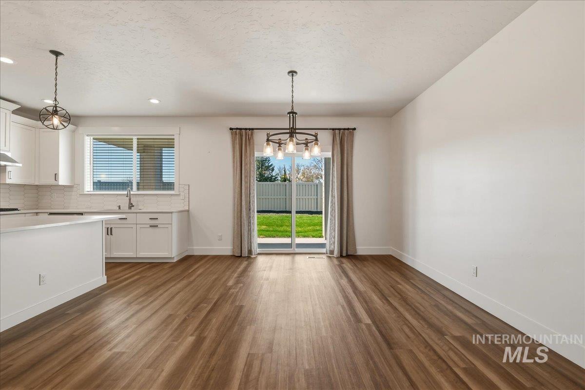 2109 North Gelding Court Middleton, ID 83644 - Photo 12 of 39 Unfurnished dining area featuring a chandelier, dark wood-style flooring, and a textured ceiling