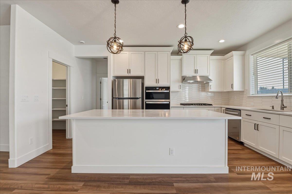 2109 North Gelding Court Middleton, ID 83644 - Photo 14 of 39 Kitchen featuring white cabinetry, stainless steel appliances, backsplash, and a kitchen island