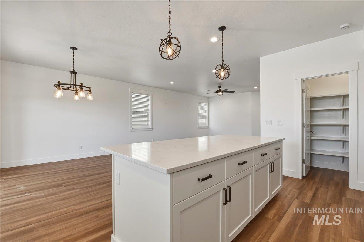 2109 North Gelding Court Middleton, ID 83644 - Photo 39 of 39 Kitchen featuring a kitchen island, white cabinets, light stone counters, dark wood-type flooring, and open floor plan