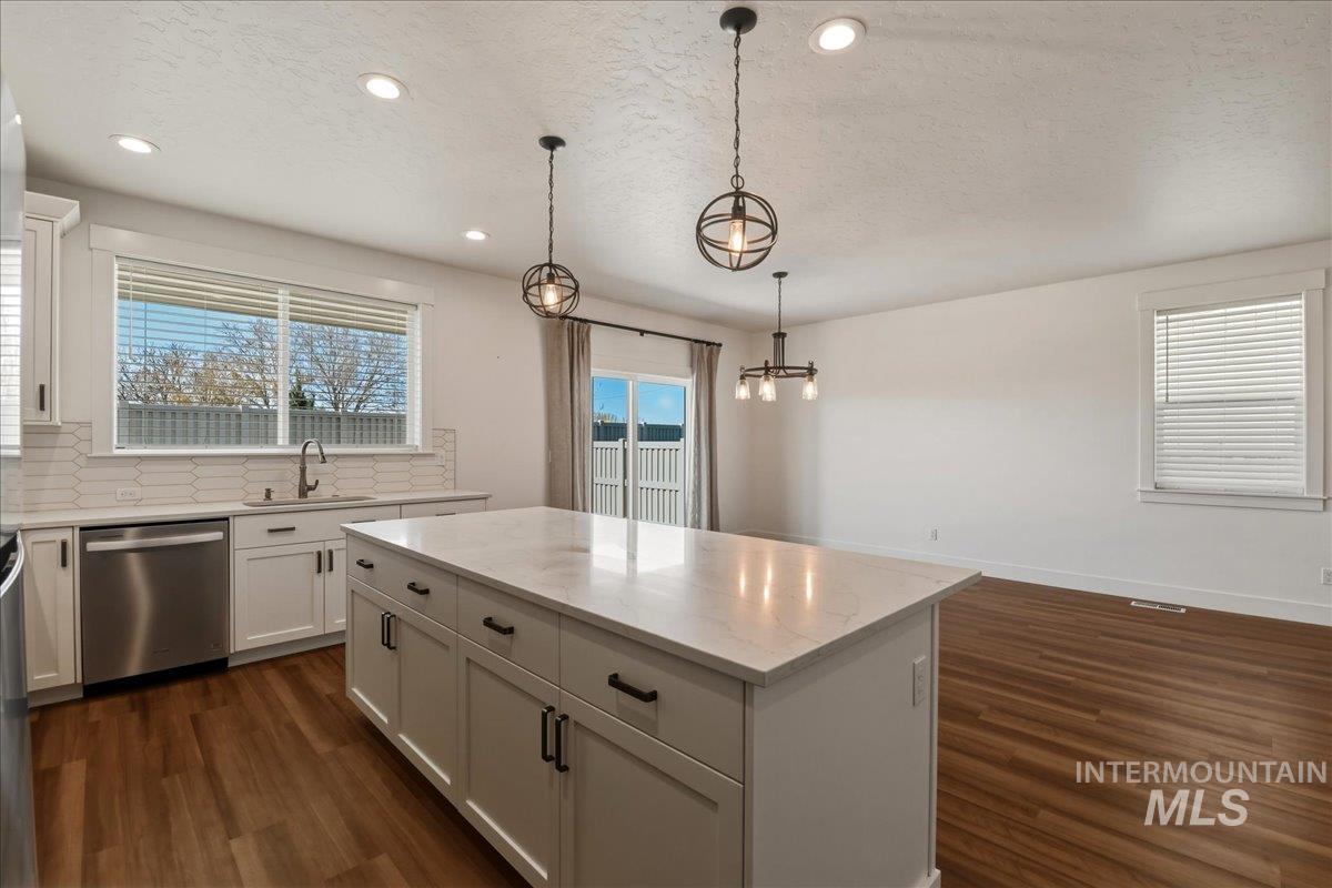 2109 North Gelding Court Middleton, ID 83644 - Photo 16 of 39 Kitchen with tasteful backsplash, white cabinetry, a textured ceiling, a center island, and dishwasher
