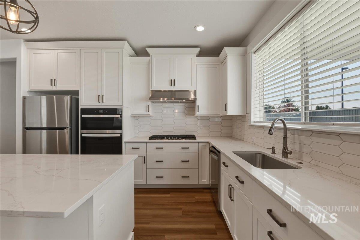 2109 North Gelding Court Middleton, ID 83644 - Photo 18 of 39 Kitchen with white cabinets, backsplash, light stone countertops, stainless steel appliances, and recessed lighting