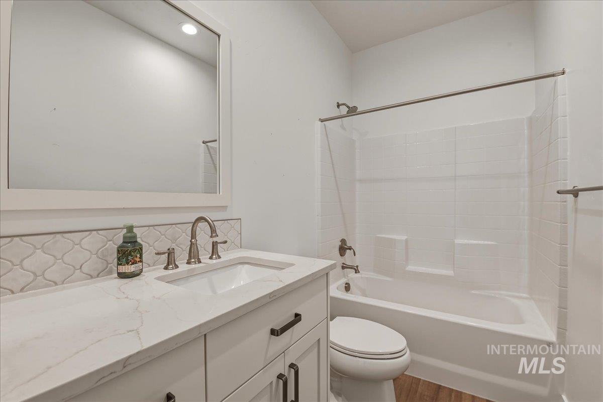 2109 North Gelding Court Middleton, ID 83644 - Photo 29 of 39 Bathroom featuring vanity, shower combination, decorative backsplash, light wood-style flooring, and recessed lighting