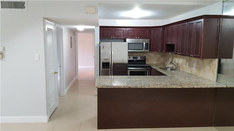 22785 Southwest 66th Avenue, Unit 103 Boca Raton, FL 33428 - Photo 1 of 8 a kitchen with kitchen island granite countertop a stove a sink and a refrigerator