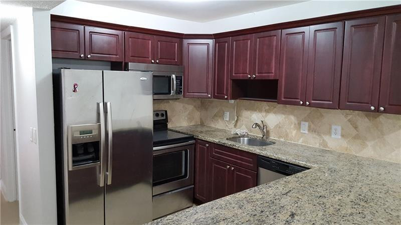 22785 Southwest 66th Avenue, Unit 103 Boca Raton, FL 33428 - Photo 2 of 8 a kitchen with stainless steel appliances granite countertop a refrigerator and a sink