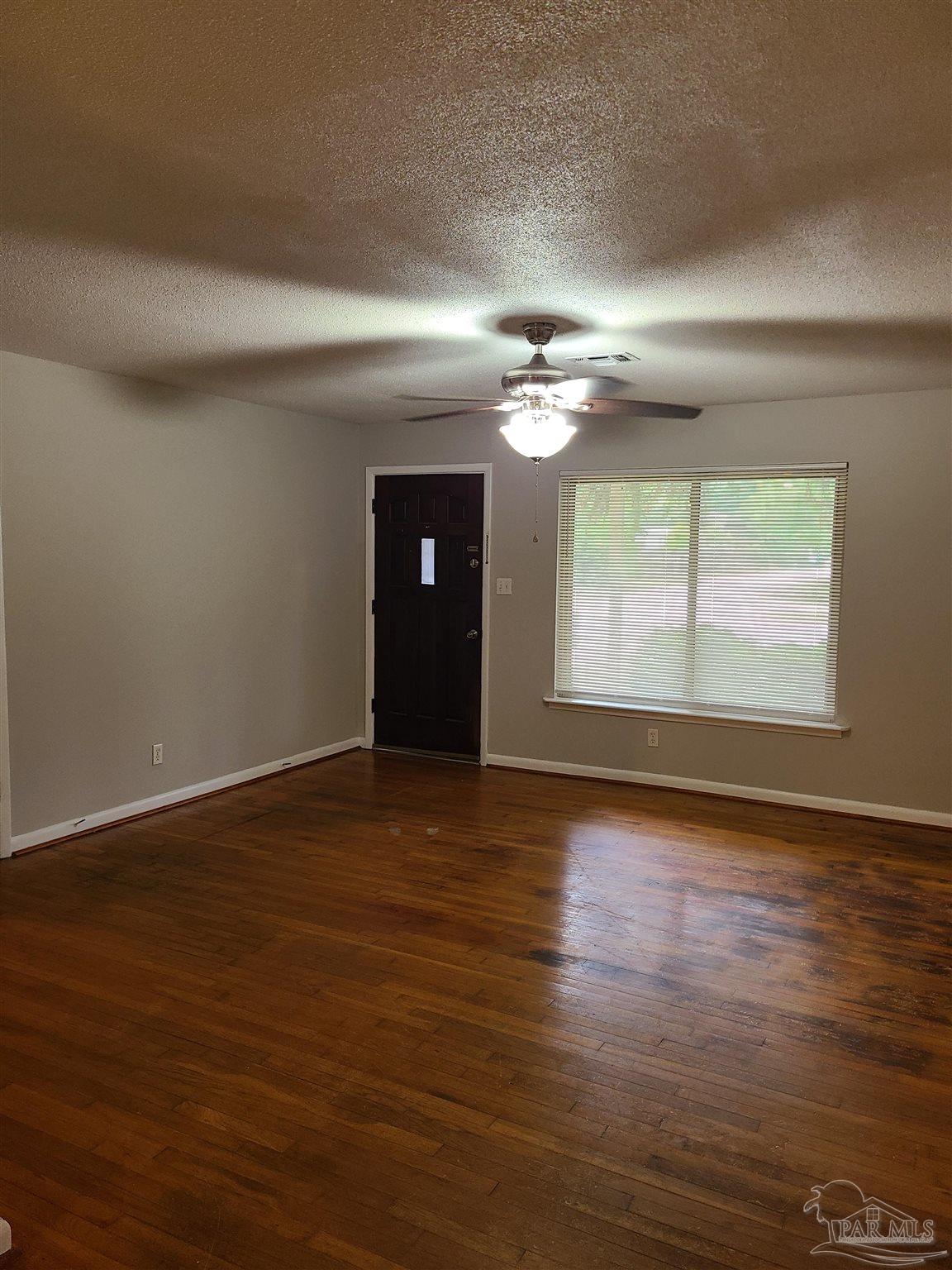 7758 Kipling Street Pensacola, FL 32514 - Photo 3 of 23 a view of an empty room with wooden floor and a window