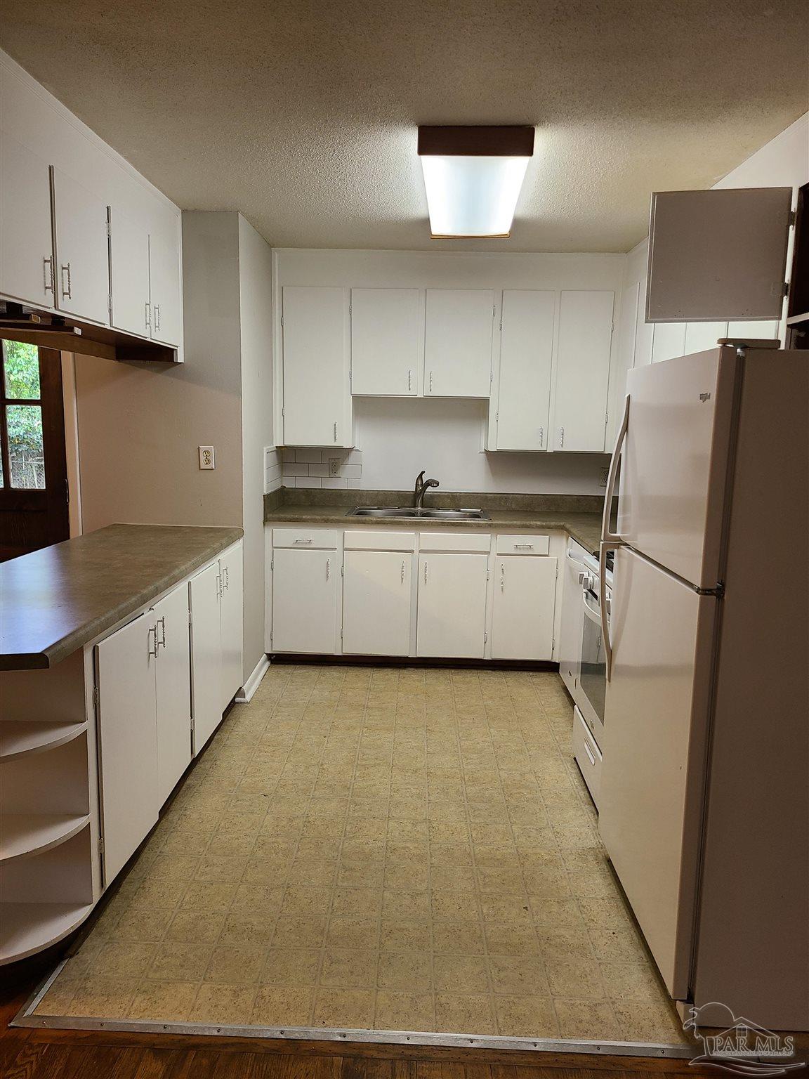 7758 Kipling Street Pensacola, FL 32514 - Photo 4 of 23 a kitchen with a sink a refrigerator and cabinets