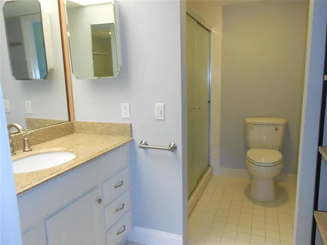 a bathroom with a granite countertop sink toilet and mirror