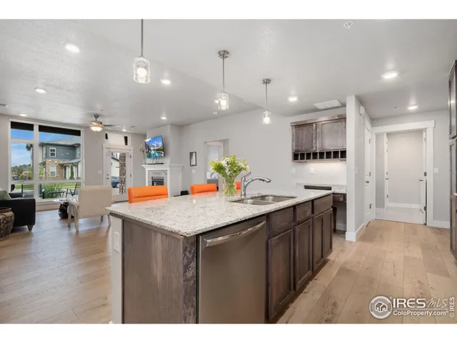 a kitchen with stainless steel appliances kitchen island granite countertop a large kitchen island a sink dishwasher and a refrigerator with wooden floor