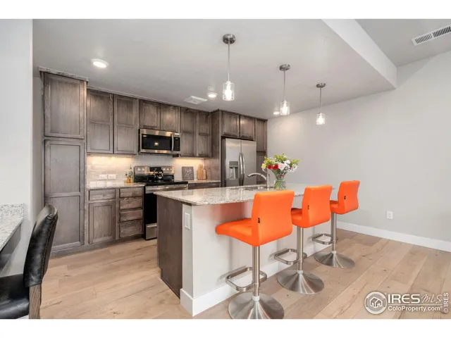 a kitchen with stainless steel appliances kitchen island granite countertop a sink refrigerator and microwave