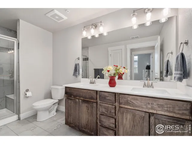 a bathroom with a sink a toilet a large mirror and shower
