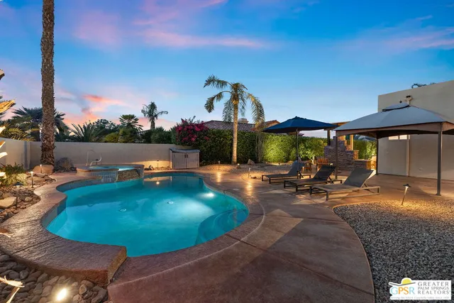 a view of a swimming pool with lawn chairs under an umbrella