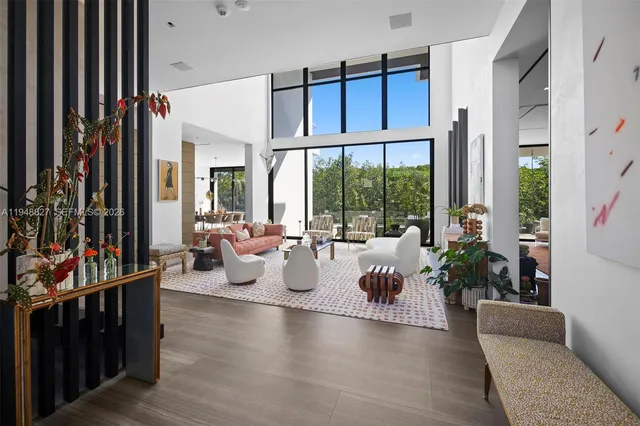 a living room with furniture large window and wooden floor