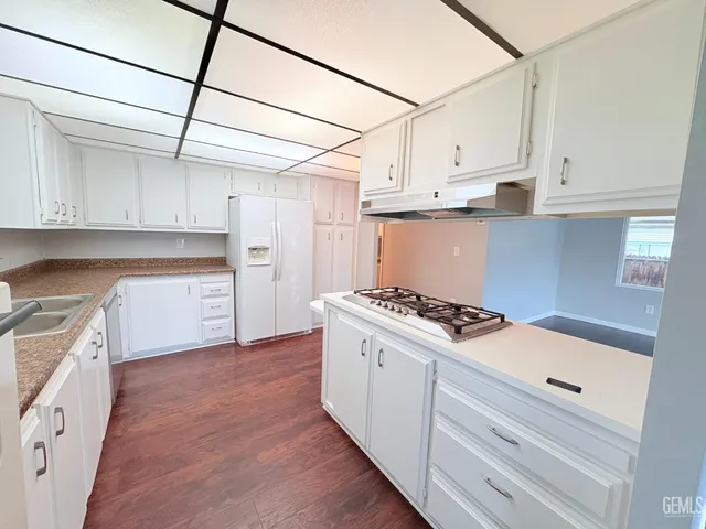 a kitchen with granite countertop a stove a sink and white cabinets
