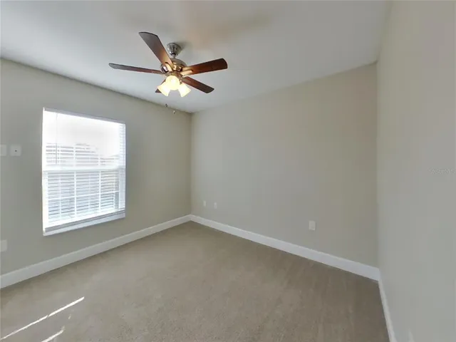 an empty room with a window and a fan