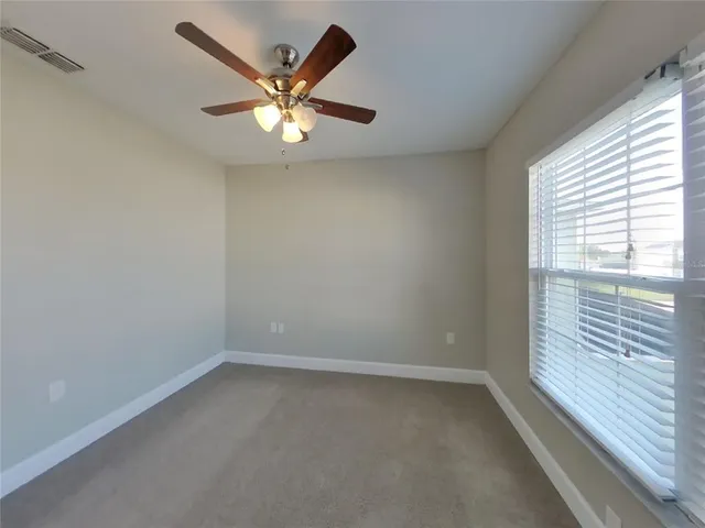 an empty room with a window and a fan