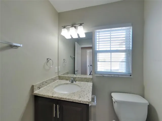a bathroom with a granite countertop sink a toilet and a mirror