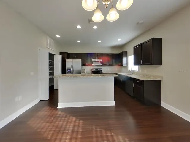 a kitchen with a chandelier stainless steel appliances cabinets and a counter top space