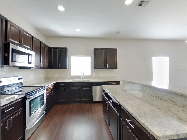 a kitchen with stainless steel appliances granite countertop wooden cabinets stove top oven and sink