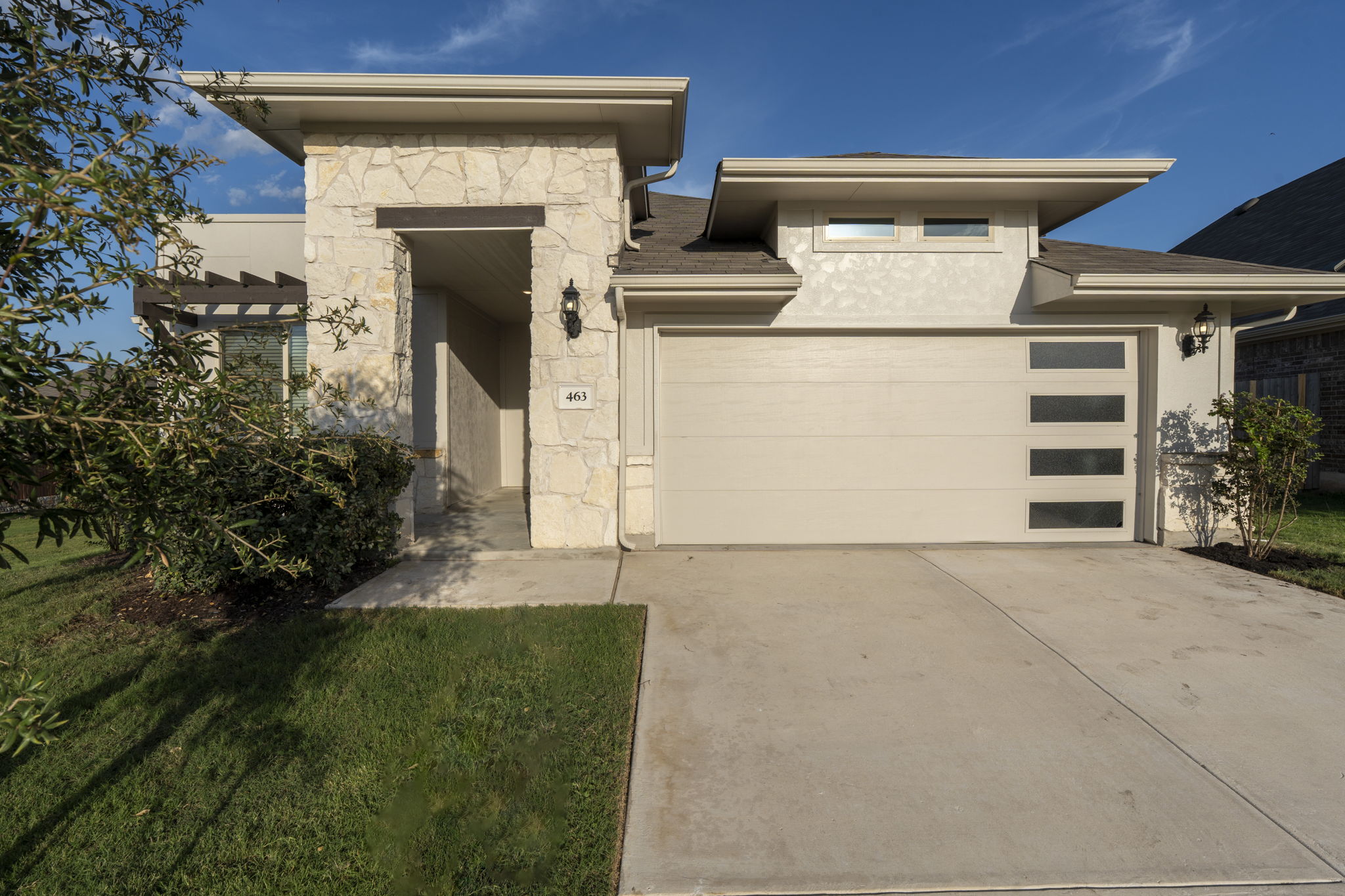 View of front of property featuring stone siding, driveway, stucco siding, and a garage