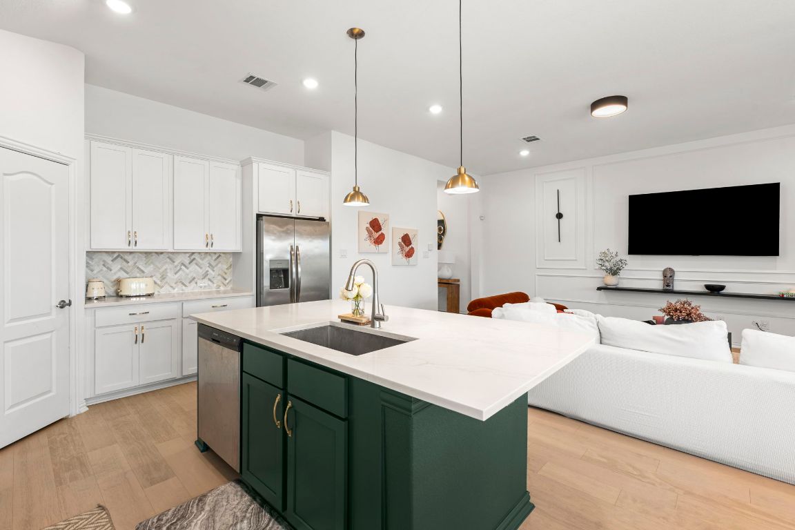 463 Oleander Loop Buda, TX 78610 - Photo 34 of 34 Kitchen with green cabinets, open floor plan, white cabinetry, appliances with stainless steel finishes, and light wood-type flooring