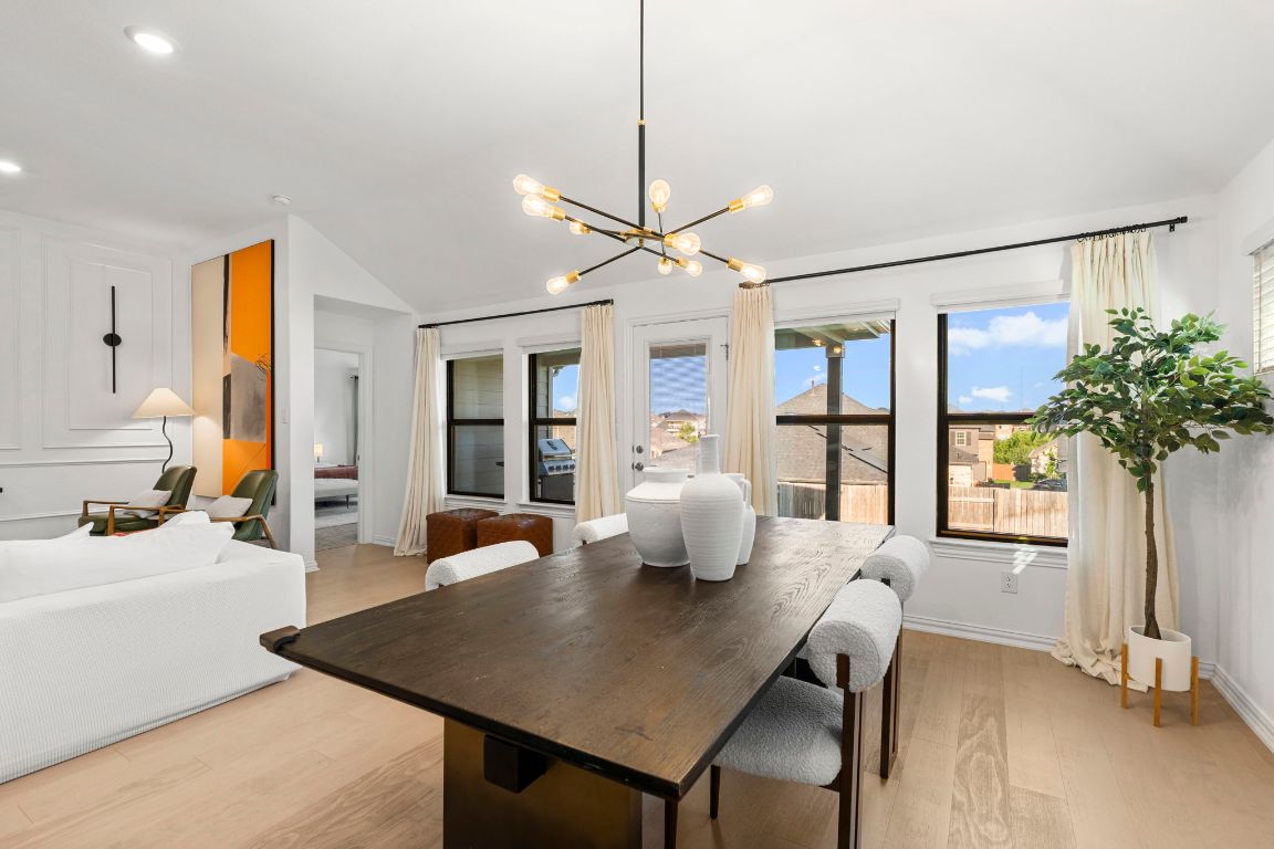463 Oleander Loop Buda, TX 78610 - Photo 10 of 34 Dining area featuring lofted ceiling, healthy amount of natural light, light wood-style floors, and a chandelier