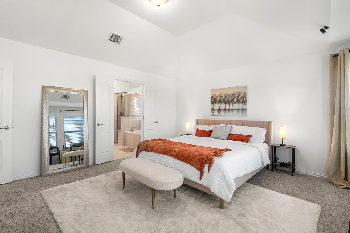 463 Oleander Loop Buda, TX 78610 - Photo 14 of 34 Carpeted bedroom featuring vaulted ceiling and ensuite bathroom