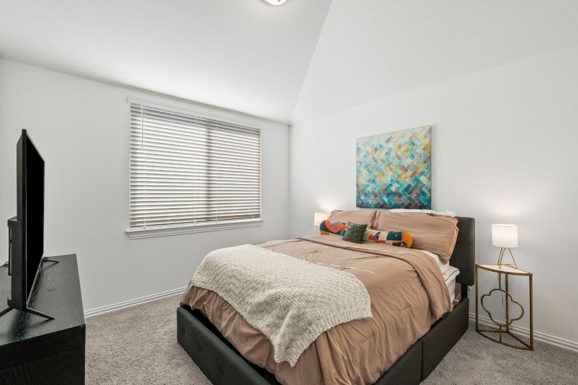 463 Oleander Loop Buda, TX 78610 - Photo 21 of 34 Carpeted bedroom featuring baseboards and high vaulted ceiling