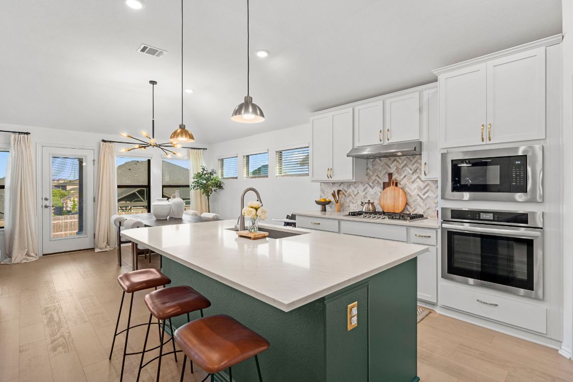 463 Oleander Loop Buda, TX 78610 - Photo 5 of 34 Kitchen with stainless steel oven, recessed lighting, an island with sink, decorative backsplash, and white cabinets