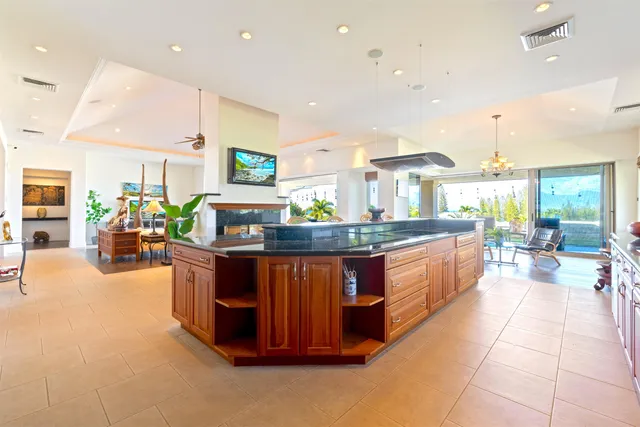 a large kitchen with stainless steel appliances a large counter top and a view of living room