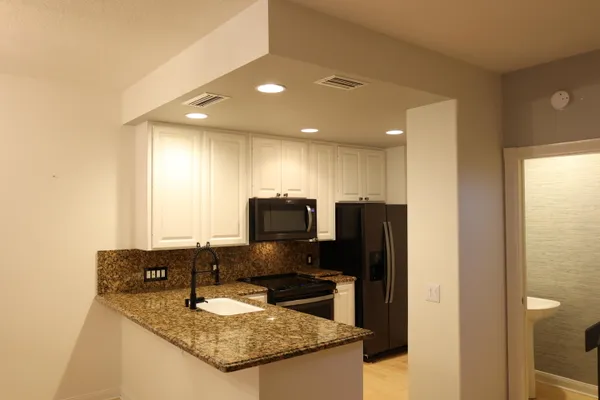 a kitchen with granite countertop a refrigerator and a stove top oven
