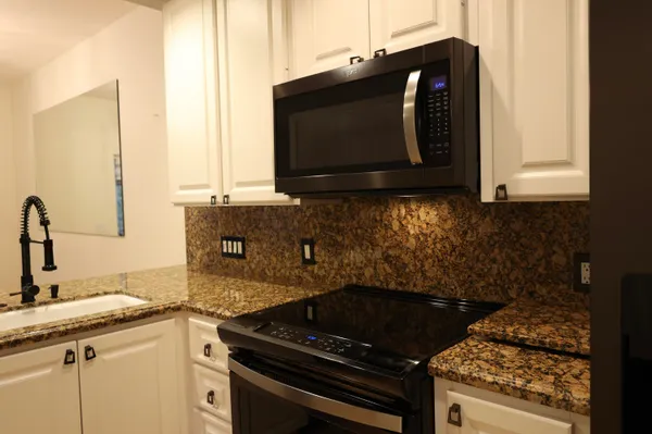 a kitchen with granite countertop a stove and a microwave