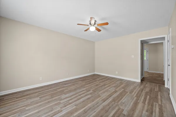 a view of an empty room with wooden floor and a window