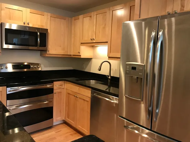 a kitchen with stainless steel appliances granite countertop a refrigerator and a stove top oven