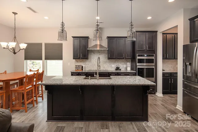 a kitchen with stainless steel appliances granite countertop a sink a stove and a refrigerator