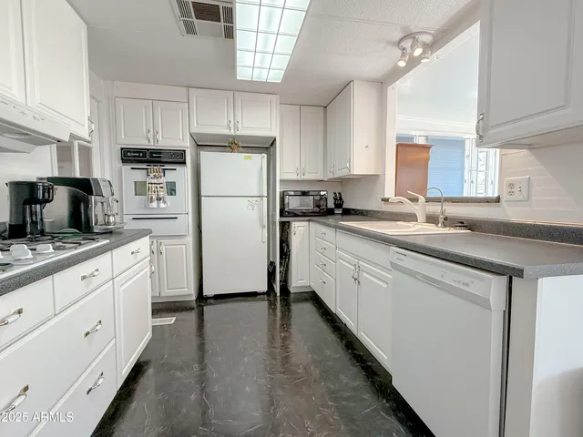 a kitchen with stainless steel appliances a refrigerator a stove a sink dishwasher a dining table and chairs with wooden floor