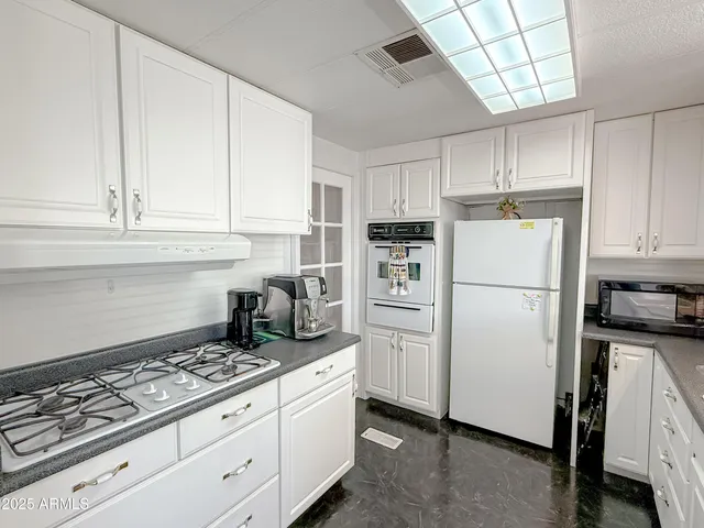 a kitchen with granite countertop white cabinets and white appliances