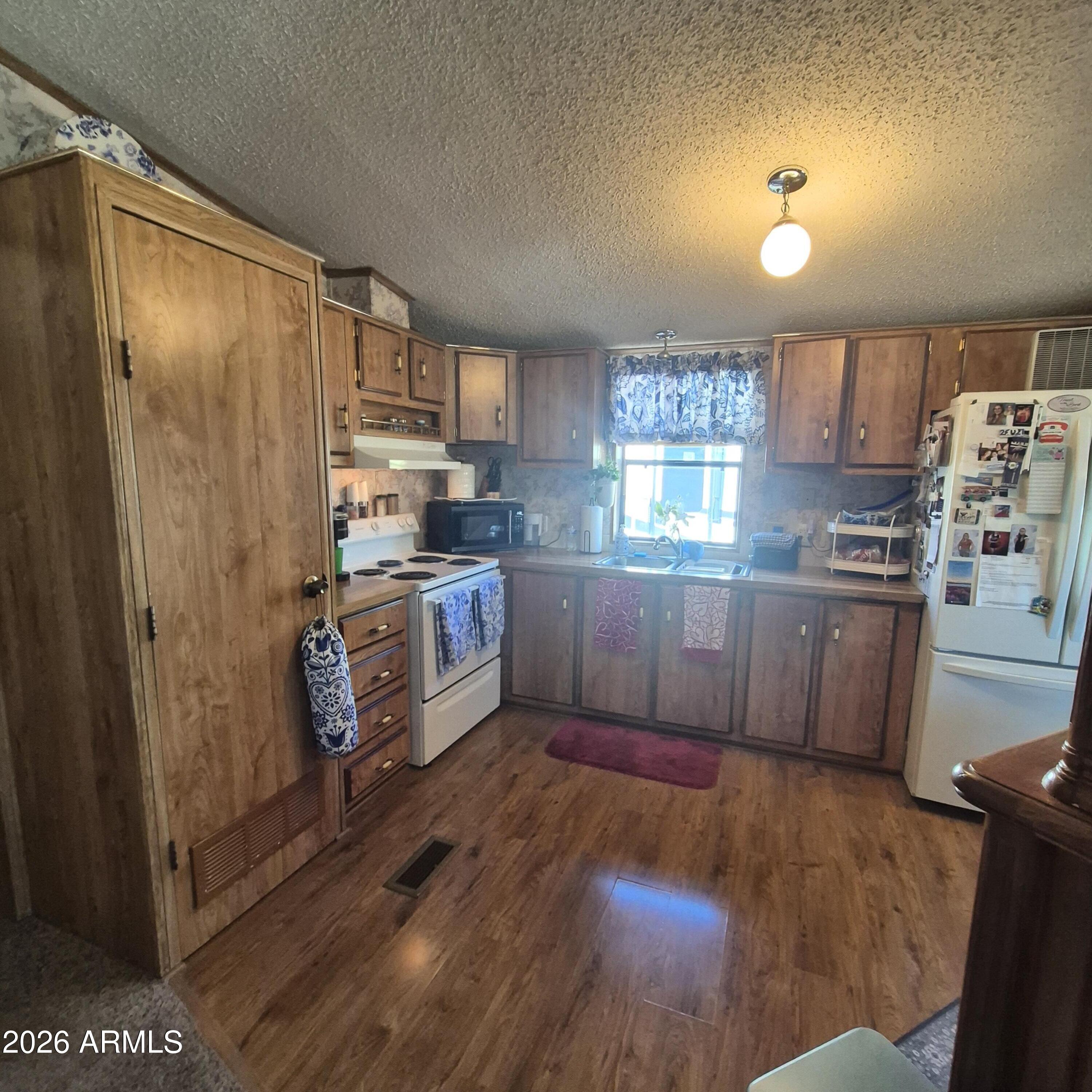 1980 South Hilton Road Apache Junction, AZ 85119 - Photo 11 of 42 a kitchen with stainless steel appliances granite countertop a refrigerator a sink dishwasher a stove and white countertops with wooden floor