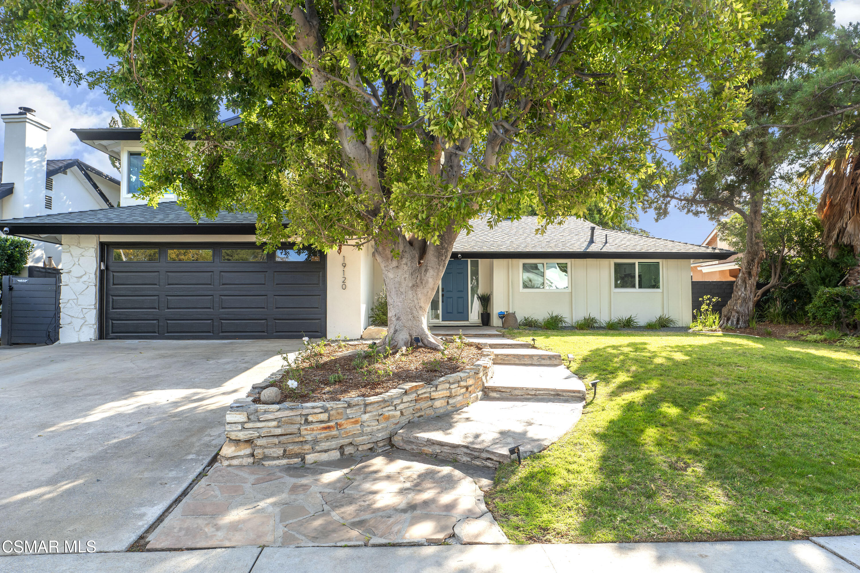 a front view of a house with a garden and trees