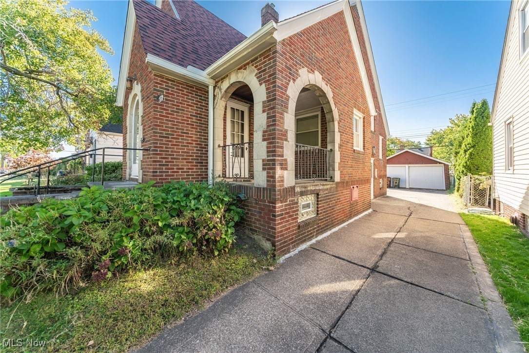 6711 Forest Avenue Parma, OH 44129 - Photo 2 of 33 View of home's exterior with a garage, brick siding, an outbuilding, roof with shingles, and a chimney