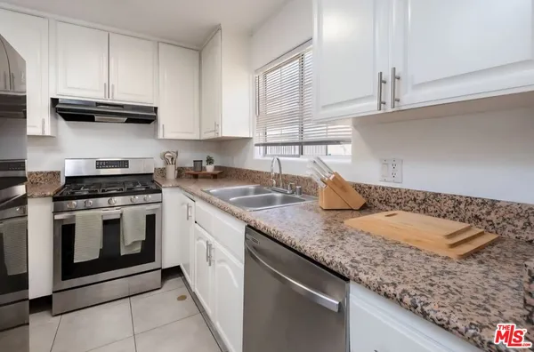 a kitchen with granite countertop stainless steel appliances sink stove and cabinets