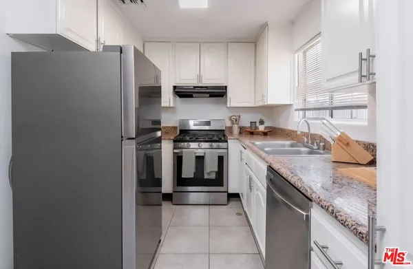 a kitchen with stainless steel appliances granite countertop a stove a refrigerator and a sink