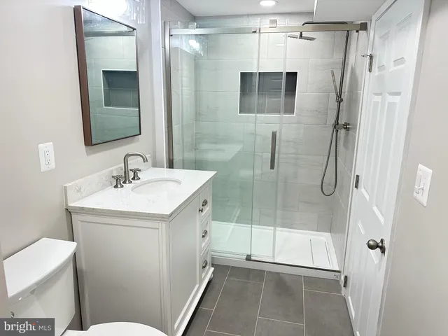 a bathroom with a shower sink mirror and toilet