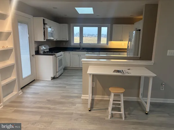 a kitchen with granite countertop a stove a sink and white cabinets