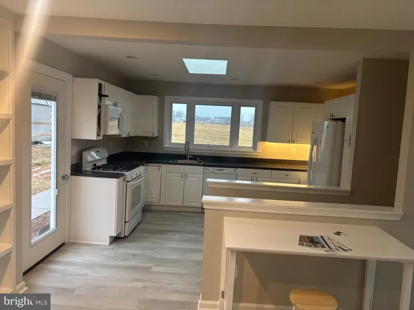 a kitchen with granite countertop a stove a sink and a microwave