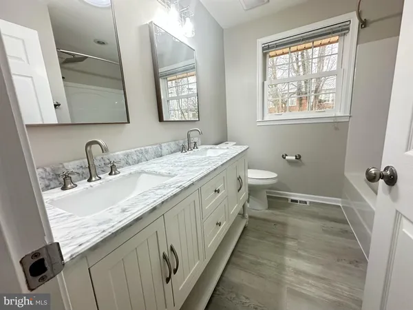 a spacious bathroom with a double vanity sink toilet mirror and a window